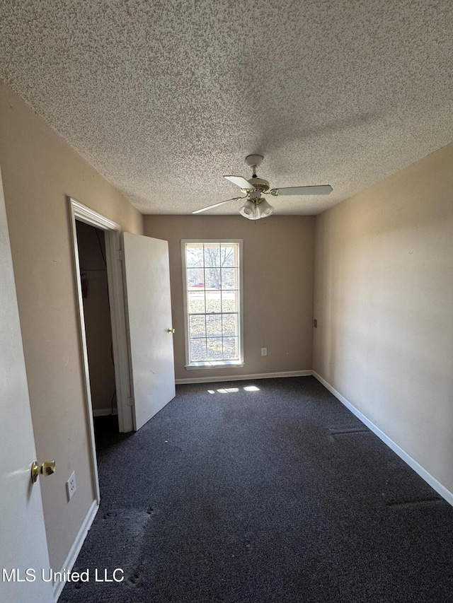 unfurnished room featuring ceiling fan, baseboards, dark colored carpet, and a textured ceiling