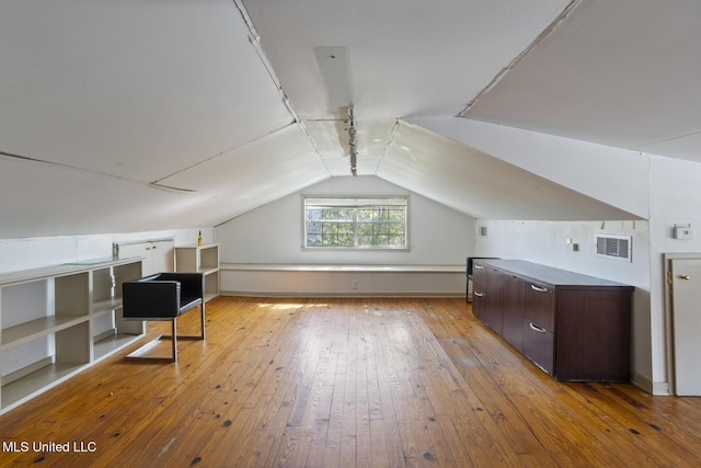 additional living space with hardwood / wood-style floors, vaulted ceiling, and visible vents