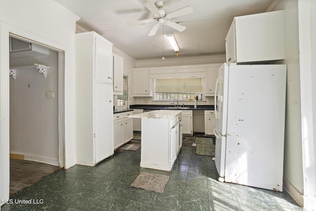 kitchen with a sink, a center island, white cabinetry, dark floors, and ceiling fan