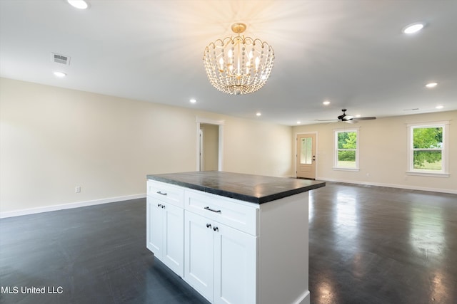 kitchen with a kitchen island, dark wood-type flooring, hanging light fixtures, white cabinets, and ceiling fan with notable chandelier