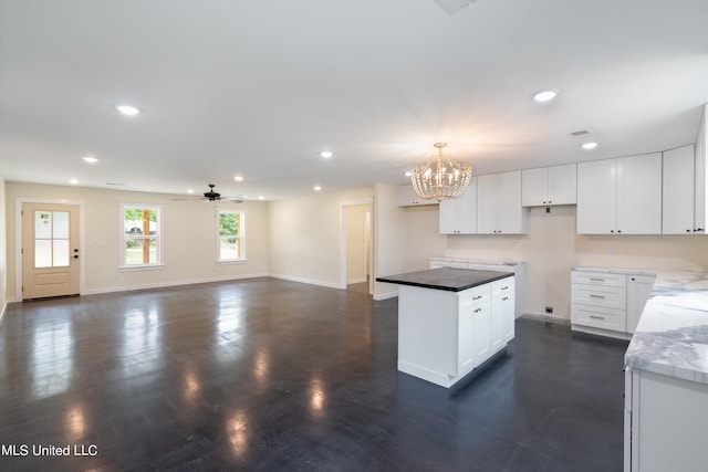 kitchen with white cabinetry, dark wood-type flooring, ceiling fan with notable chandelier, decorative light fixtures, and a center island