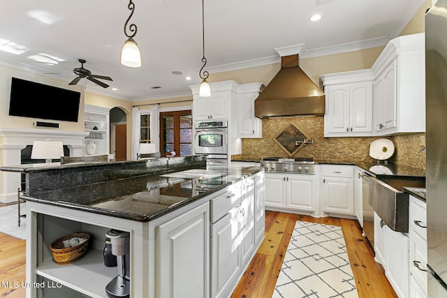 kitchen with wall chimney range hood, a center island, and white cabinets