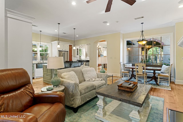 living room featuring ornamental molding, light hardwood / wood-style floors, and ceiling fan