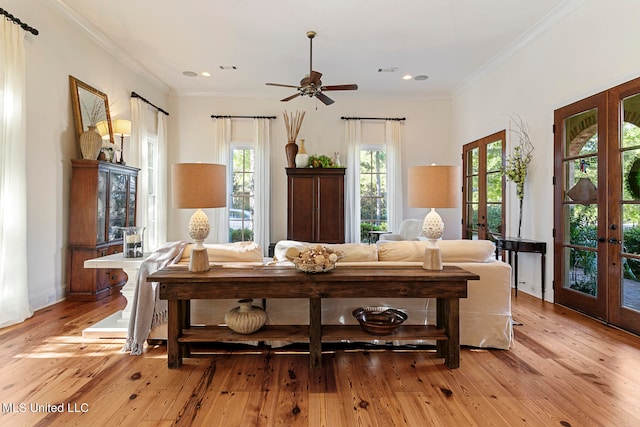 living room featuring french doors, light hardwood / wood-style floors, crown molding, and ceiling fan