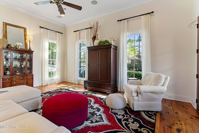 living room with a wealth of natural light, hardwood / wood-style floors, crown molding, and ceiling fan