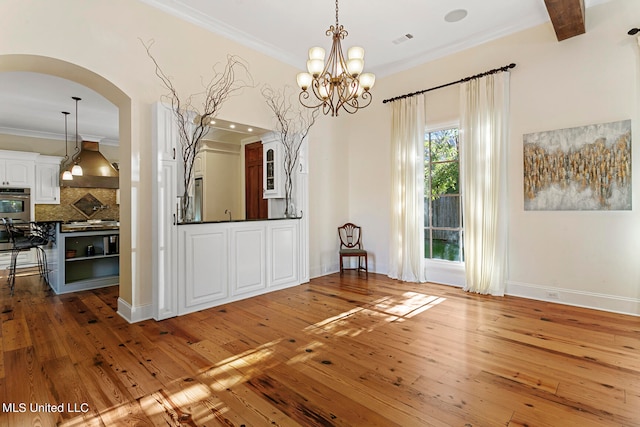 unfurnished dining area with ornamental molding, a notable chandelier, and hardwood / wood-style floors