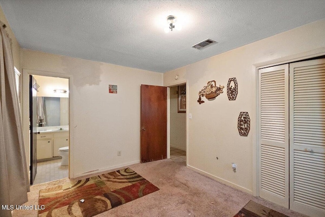 2530 Crestleigh Mnr, Jackson, MS 39204 - bedroom with a closet, a textured ceiling, baseboards, ensuite bathroom, and light carpet