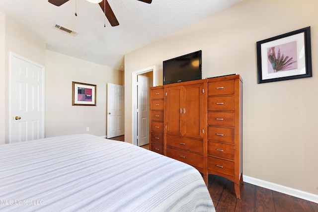 bedroom with ceiling fan, a textured ceiling, and dark wood-type flooring