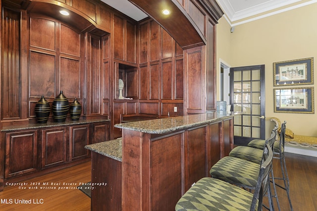 bar with dark hardwood / wood-style floors, dark stone countertops, and crown molding