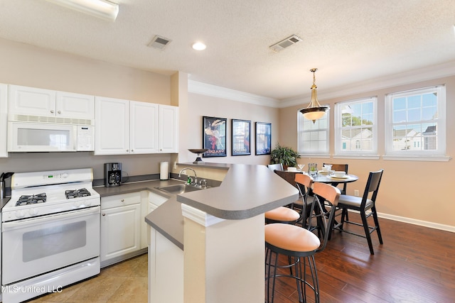 kitchen featuring hardwood / wood-style floors, white appliances, sink, ornamental molding, and white cabinetry