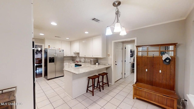 136 Westlake Dr, Brandon, MS 39047 - kitchen featuring stainless steel fridge with ice dispenser, a peninsula, white cabinetry, light tile patterned flooring, and a breakfast bar area