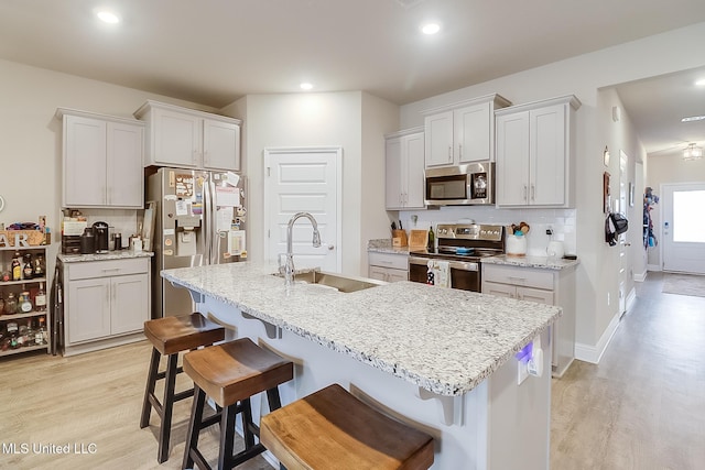 kitchen featuring appliances with stainless steel finishes, sink, a center island with sink, and a kitchen breakfast bar