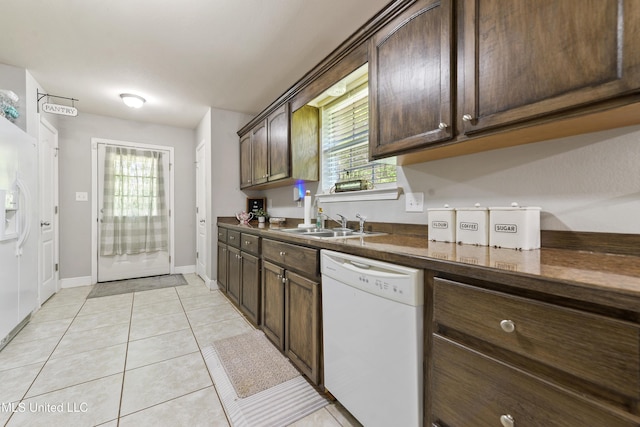 22807 Alamosa Dr, Moss Point, MS 39562 - kitchen featuring dark brown cabinetry, white appliances, light tile patterned floors, dark countertops, and a sink