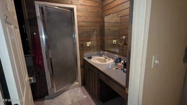 bathroom featuring a shower with shower door, wood walls, tile patterned floors, and vanity