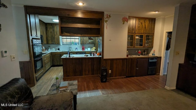 kitchen with kitchen peninsula, light hardwood / wood-style flooring, double oven, ornamental molding, and sink