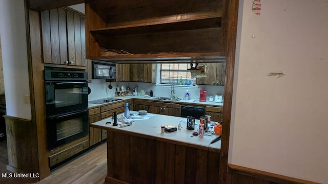 kitchen featuring black appliances, kitchen peninsula, hardwood / wood-style floors, and sink