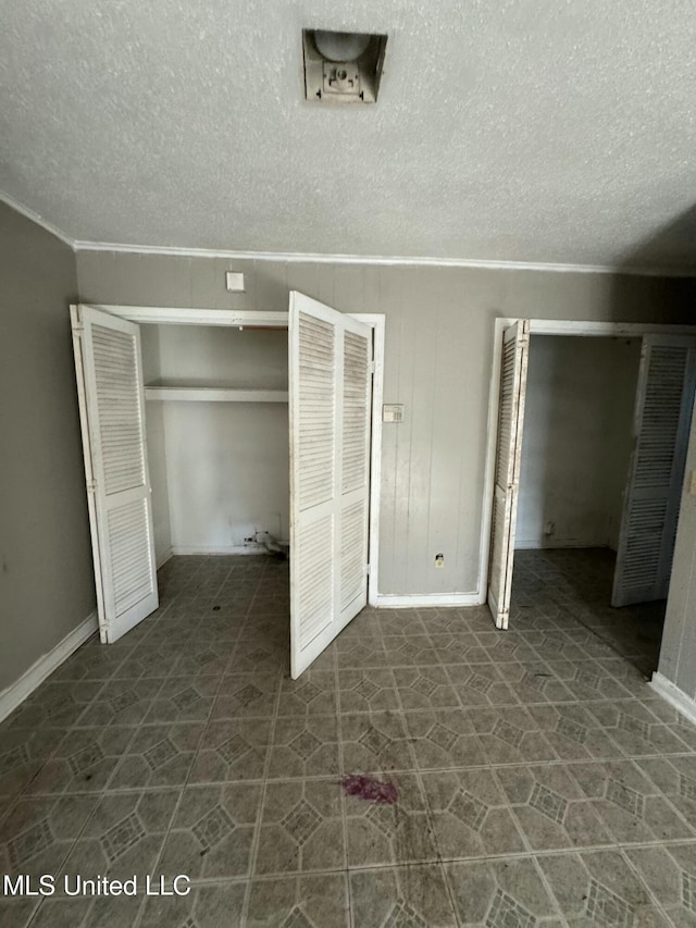 unfurnished bedroom featuring wooden walls, a closet, and a textured ceiling