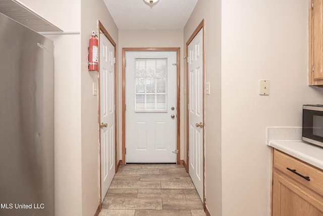 doorway featuring a textured ceiling and light hardwood / wood-style flooring