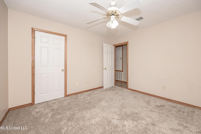 carpeted empty room featuring ceiling fan and a textured ceiling