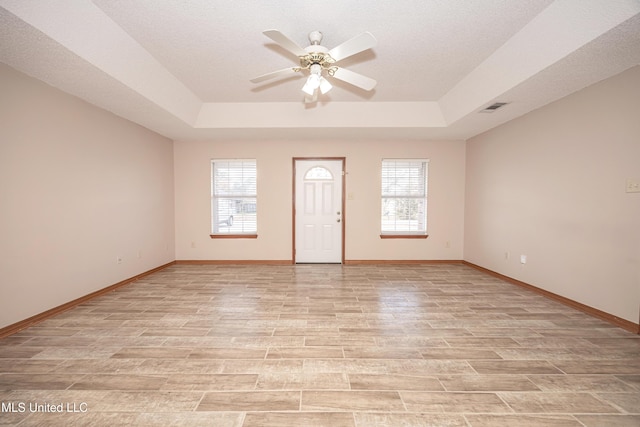 spare room featuring plenty of natural light, a raised ceiling, and ceiling fan