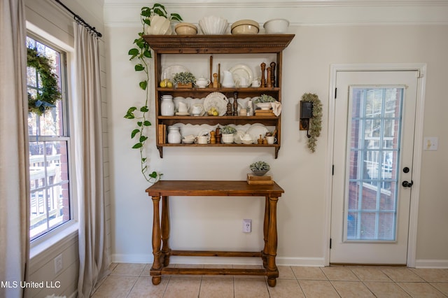 doorway to outside with light tile patterned flooring and ornamental molding