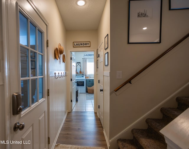 hallway with washer / dryer, a textured ceiling, and hardwood / wood-style flooring