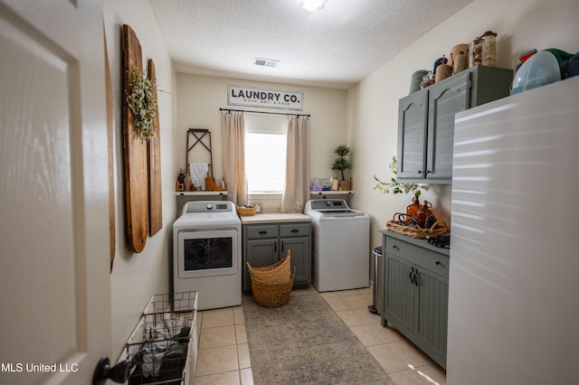 laundry area with light tile patterned flooring, cabinets, and a textured ceiling