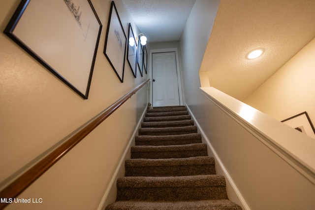 stairway featuring carpet and a textured ceiling