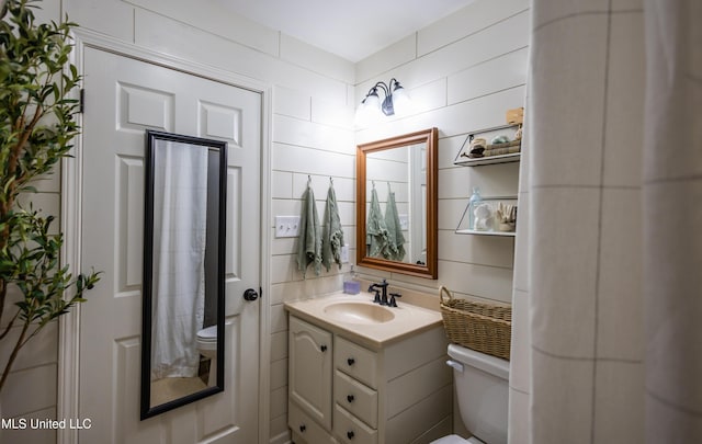 bathroom featuring vanity, tile walls, and toilet