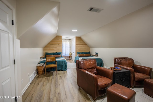 bedroom featuring wooden walls, light hardwood / wood-style floors, and lofted ceiling