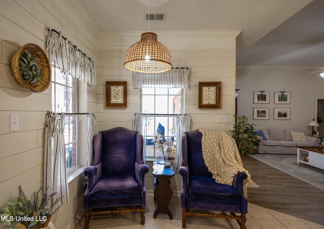 sitting room with hardwood / wood-style floors, ceiling fan, crown molding, and a textured ceiling