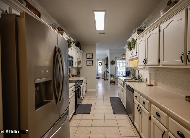 kitchen featuring sink, crown molding, decorative backsplash, light tile patterned floors, and stainless steel appliances