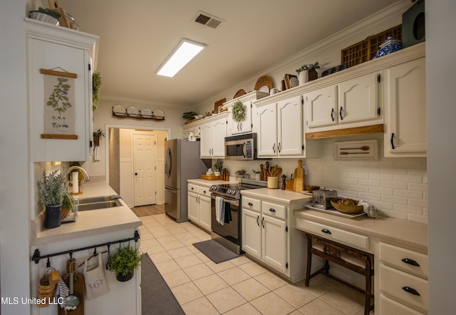 kitchen featuring ornamental molding, stainless steel appliances, sink, white cabinetry, and light tile patterned flooring