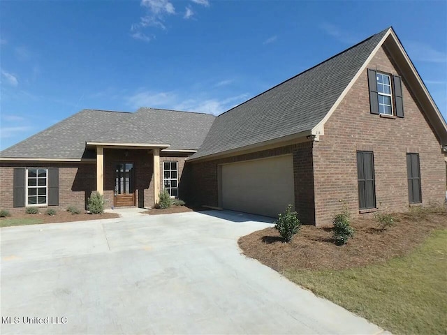 view of front of property with brick siding, driveway, and a shingled roof