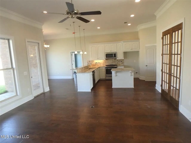 kitchen with ornamental molding, decorative backsplash, appliances with stainless steel finishes, white cabinets, and dark wood-style flooring