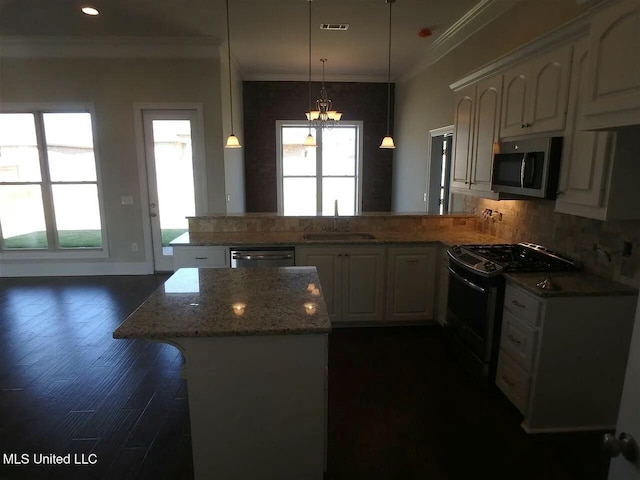 kitchen with a peninsula, a sink, stainless steel appliances, white cabinetry, and crown molding