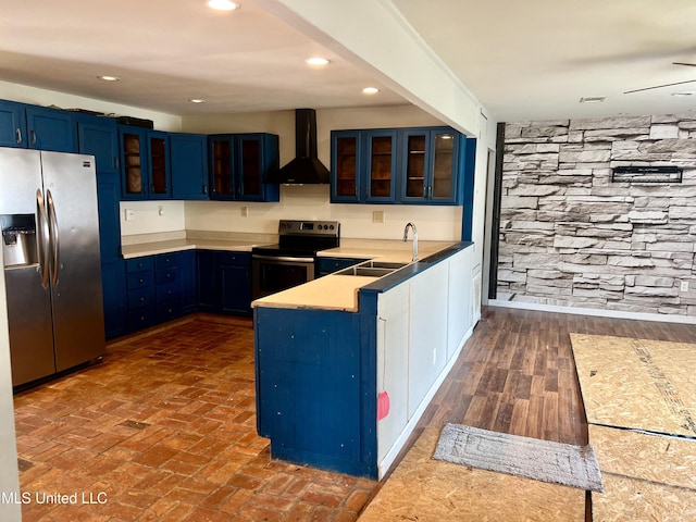 kitchen with blue cabinetry, stainless steel appliances, sink, and wall chimney range hood