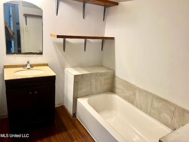 bathroom with wood-type flooring, a washtub, and vanity