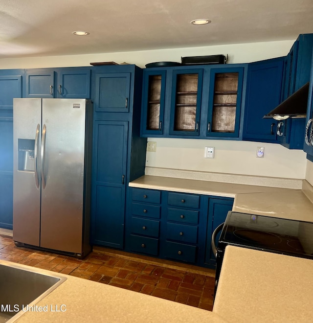 kitchen with blue cabinetry, stainless steel fridge, and ventilation hood