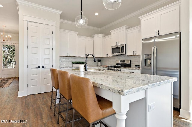 kitchen with pendant lighting, sink, white cabinets, an island with sink, and stainless steel appliances