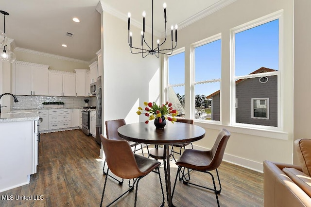 dining area featuring sink, crown molding, dark wood-type flooring, and an inviting chandelier