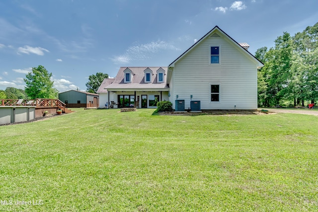 back of house featuring central air condition unit, a yard, and metal roof