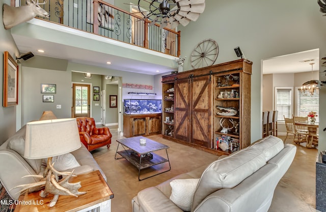 living area with an inviting chandelier, a barn door, a towering ceiling, and recessed lighting