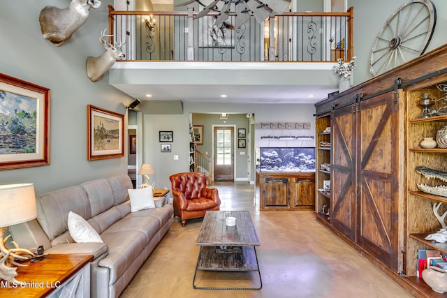 living room featuring a barn door, concrete floors, stairway, and a towering ceiling