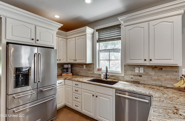 kitchen with light stone counters, a sink, appliances with stainless steel finishes, and tasteful backsplash