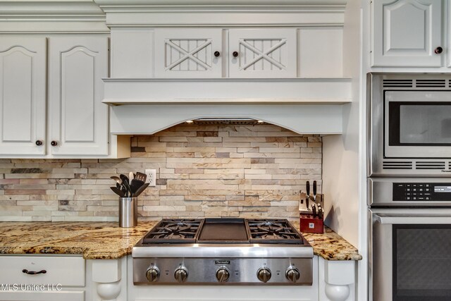 kitchen featuring white cabinetry, light stone countertops, appliances with stainless steel finishes, and tasteful backsplash