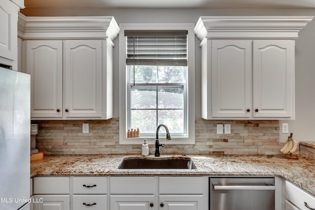 kitchen featuring stainless steel dishwasher, a sink, white cabinetry, and decorative backsplash