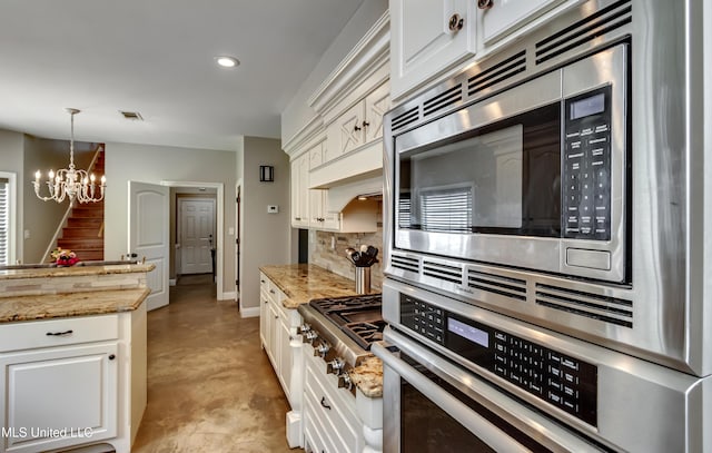 kitchen with an inviting chandelier, white cabinetry, backsplash, hanging light fixtures, and stainless steel appliances