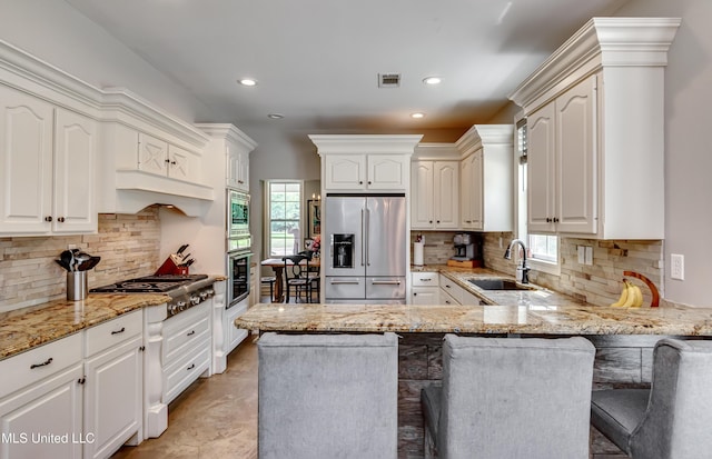 kitchen with visible vents, a sink, a peninsula, stainless steel appliances, and a wealth of natural light