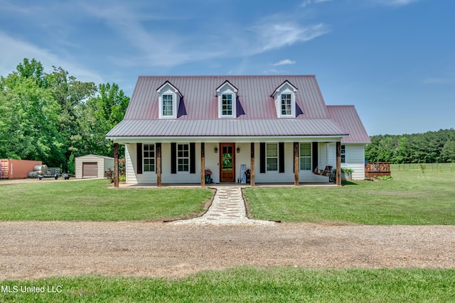 view of front of property featuring a porch, an outbuilding, metal roof, and a front lawn